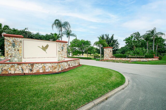 community sign with a yard and curved driveway