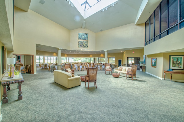 living room featuring high vaulted ceiling, ornate columns, a skylight, and carpet flooring