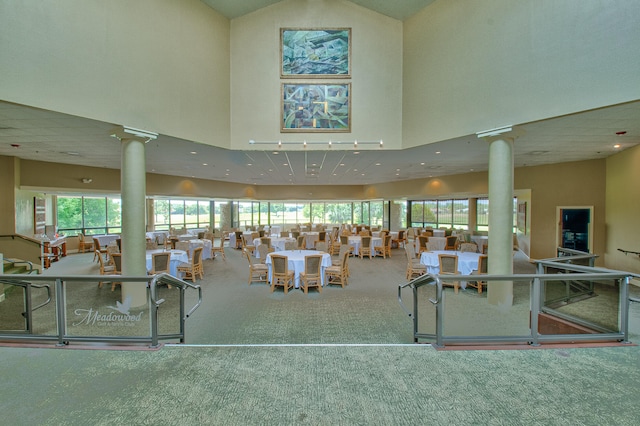 gym with carpet flooring, decorative columns, and a towering ceiling