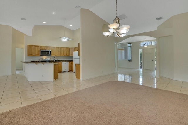 kitchen with stainless steel appliances, light colored carpet, high vaulted ceiling, and decorative light fixtures