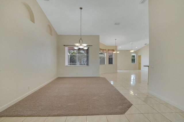 spare room with ceiling fan with notable chandelier, a high ceiling, and light tile patterned flooring