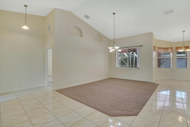 empty room with an inviting chandelier, light colored carpet, and high vaulted ceiling