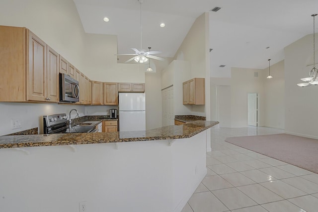 kitchen with pendant lighting, dark stone countertops, stainless steel appliances, kitchen peninsula, and light brown cabinets