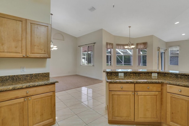 kitchen featuring light tile patterned flooring, pendant lighting, lofted ceiling, dark stone counters, and an inviting chandelier