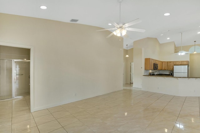 unfurnished living room with ceiling fan, high vaulted ceiling, and light tile patterned floors