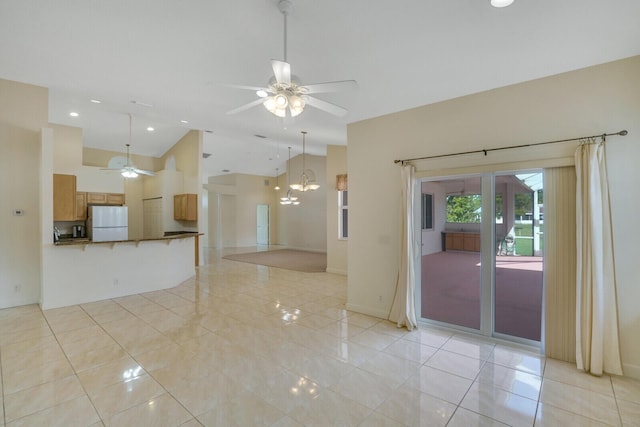 spare room with light tile patterned flooring, high vaulted ceiling, and ceiling fan with notable chandelier