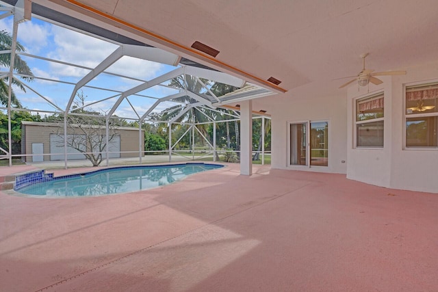 view of pool with ceiling fan, a storage shed, a patio area, and glass enclosure