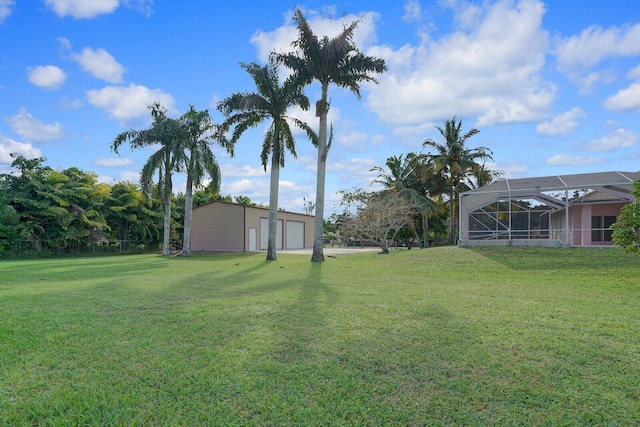 view of yard with a garage, a lanai, and an outdoor structure