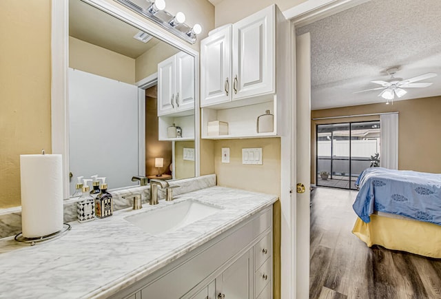 bathroom with ceiling fan, vanity, a textured ceiling, and hardwood / wood-style floors