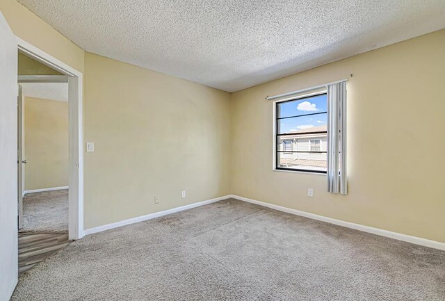 carpeted spare room with a textured ceiling