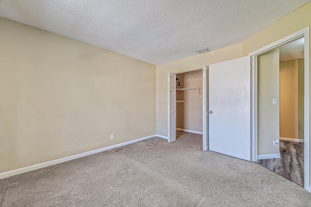 unfurnished bedroom with light colored carpet, a closet, and a textured ceiling