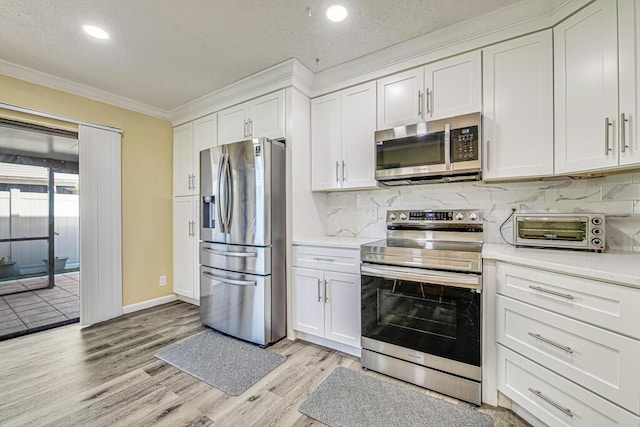 kitchen featuring white cabinets, stainless steel appliances, tasteful backsplash, light hardwood / wood-style flooring, and crown molding