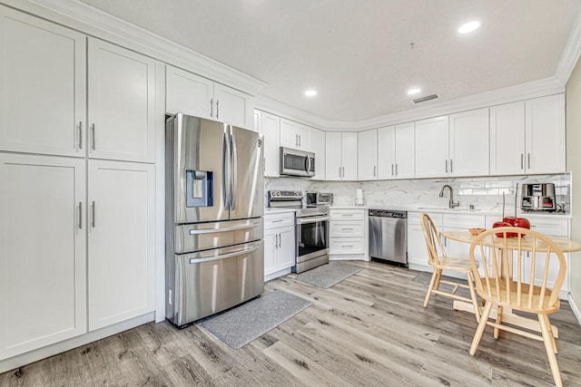 kitchen with white cabinets, light wood-type flooring, appliances with stainless steel finishes, and sink