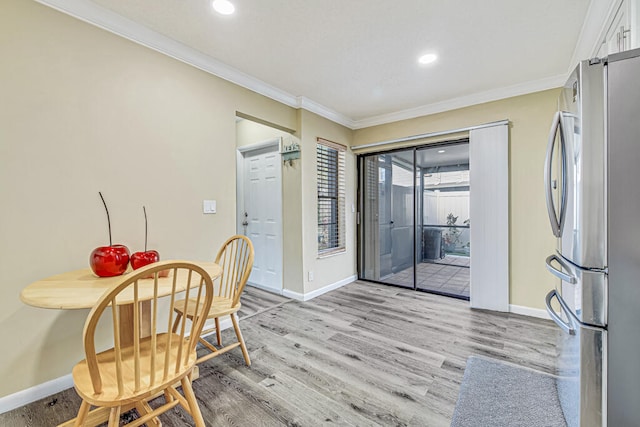 kitchen with white cabinets, light wood-type flooring, stainless steel fridge, and ornamental molding