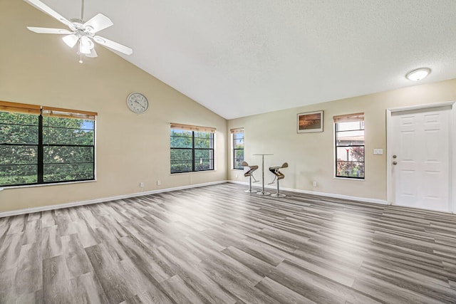 unfurnished living room with ceiling fan, light hardwood / wood-style floors, a textured ceiling, and high vaulted ceiling