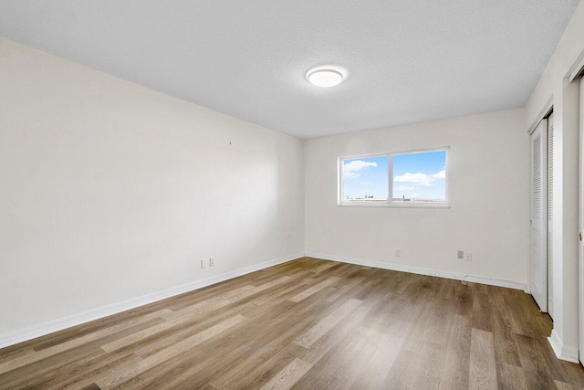 unfurnished bedroom with a textured ceiling, light wood-type flooring, and a closet