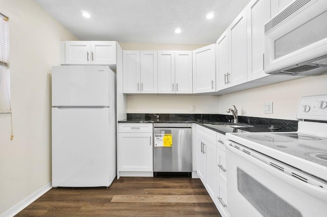 kitchen featuring white appliances, dark wood-type flooring, white cabinets, dark stone countertops, and sink