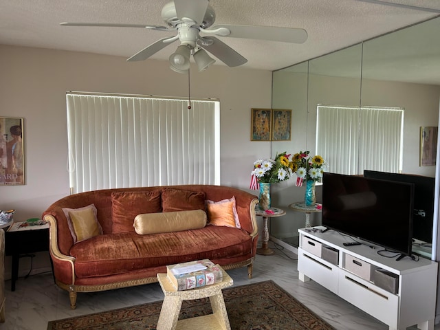 living room featuring ceiling fan and a textured ceiling