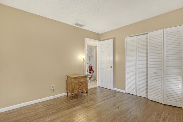 unfurnished bedroom featuring light hardwood / wood-style floors, a closet, and a textured ceiling