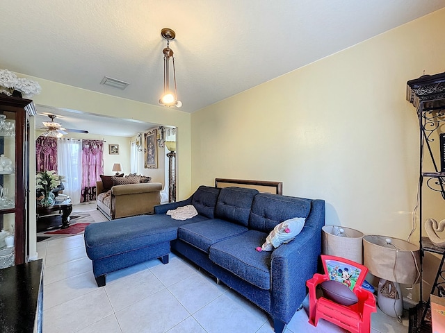 living room with ceiling fan, light tile patterned floors, and a textured ceiling