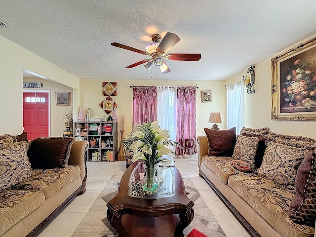 living room with ceiling fan, light tile patterned floors, and a textured ceiling