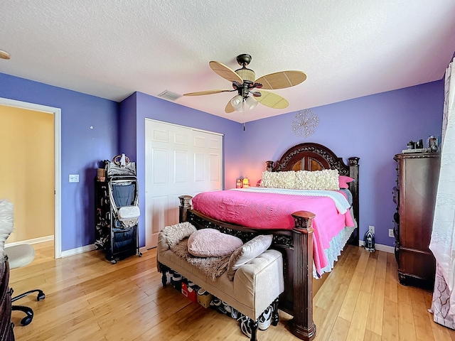 bedroom featuring a textured ceiling, light wood-type flooring, a closet, and ceiling fan