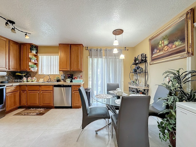 kitchen with appliances with stainless steel finishes, a textured ceiling, decorative light fixtures, and light tile patterned floors