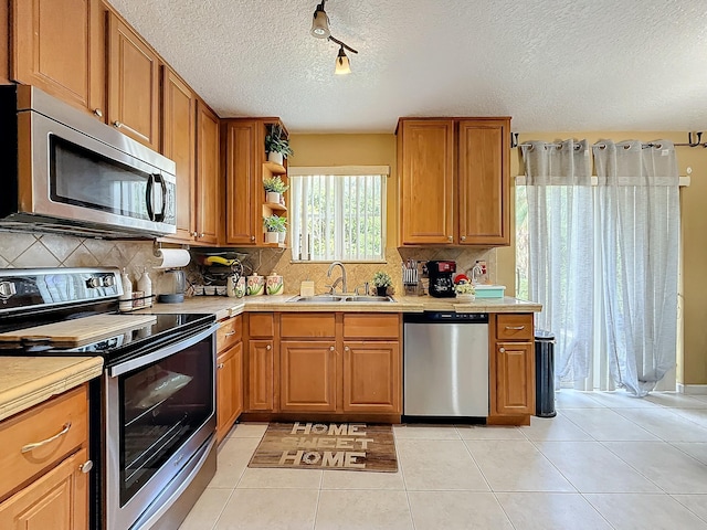 kitchen with tasteful backsplash, sink, light tile patterned flooring, and appliances with stainless steel finishes