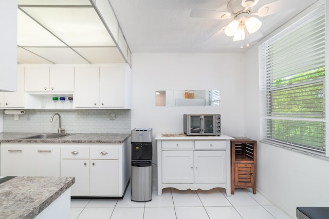 kitchen featuring white cabinets, decorative backsplash, light tile patterned floors, and ceiling fan