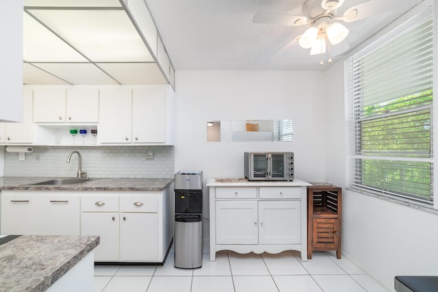 kitchen with tasteful backsplash, white cabinetry, sink, and light tile patterned floors