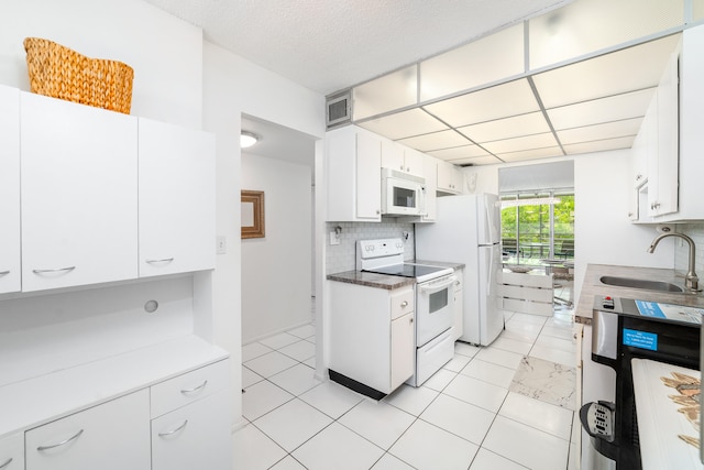 kitchen with white cabinetry, white appliances, sink, light tile patterned floors, and backsplash