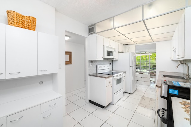 kitchen featuring sink, white appliances, light tile patterned floors, backsplash, and white cabinets