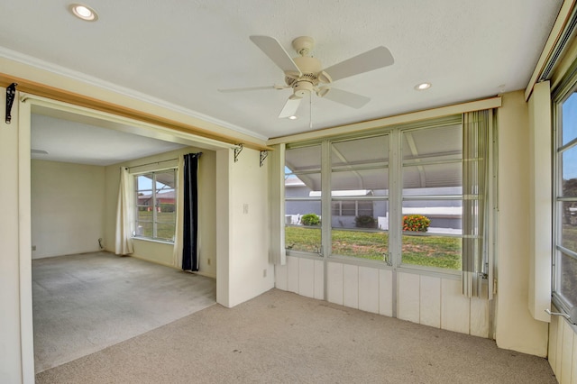 carpeted spare room with ceiling fan and crown molding