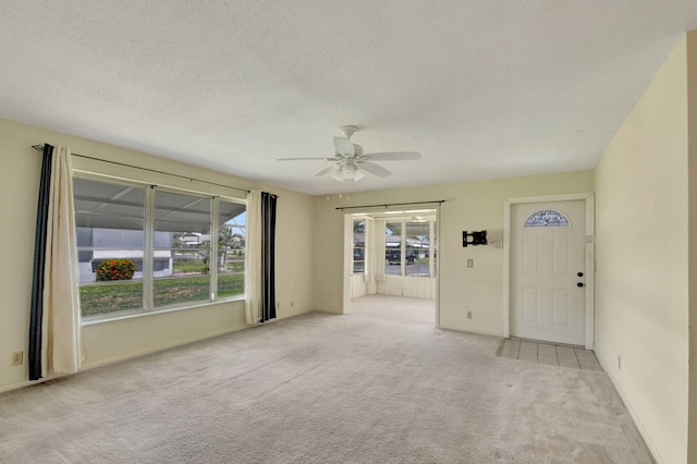 unfurnished living room featuring ceiling fan, light carpet, and a textured ceiling