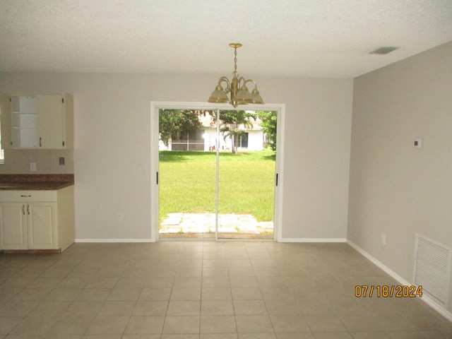 unfurnished dining area featuring a chandelier, a wealth of natural light, and light tile patterned floors