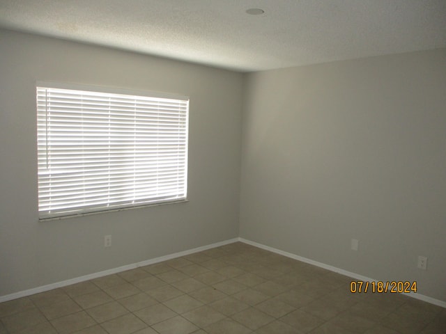 tiled spare room featuring a textured ceiling