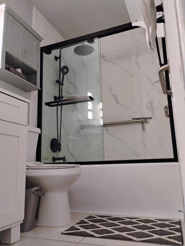 bathroom featuring tile patterned flooring, bath / shower combo with glass door, and toilet