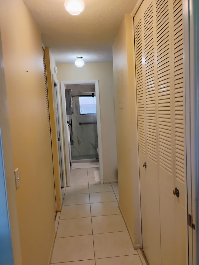 corridor with light tile patterned floors and a textured ceiling