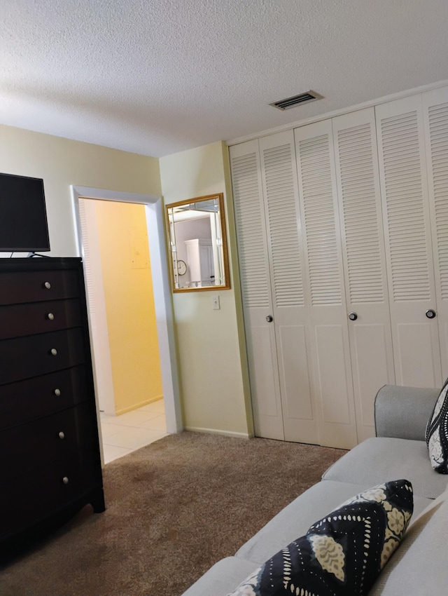 carpeted bedroom featuring a textured ceiling and a closet