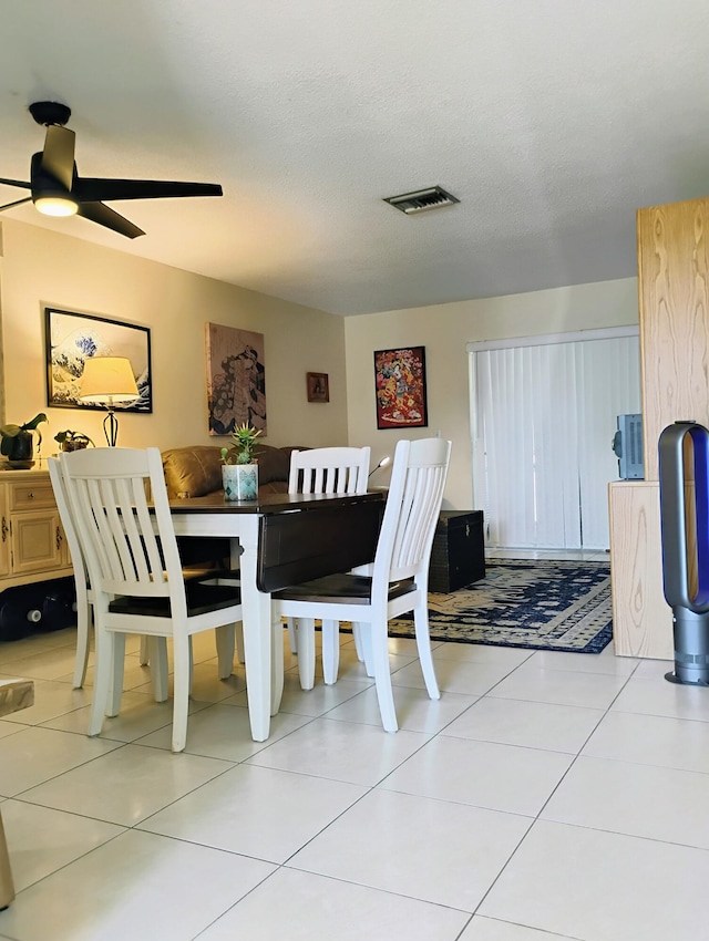 tiled dining area with a textured ceiling and ceiling fan