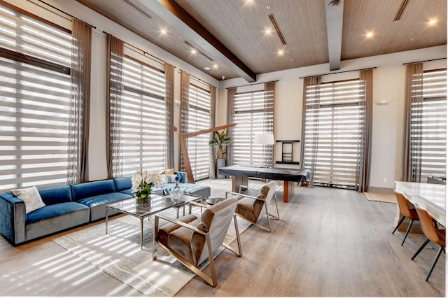 living room with beamed ceiling, plenty of natural light, and light wood-type flooring