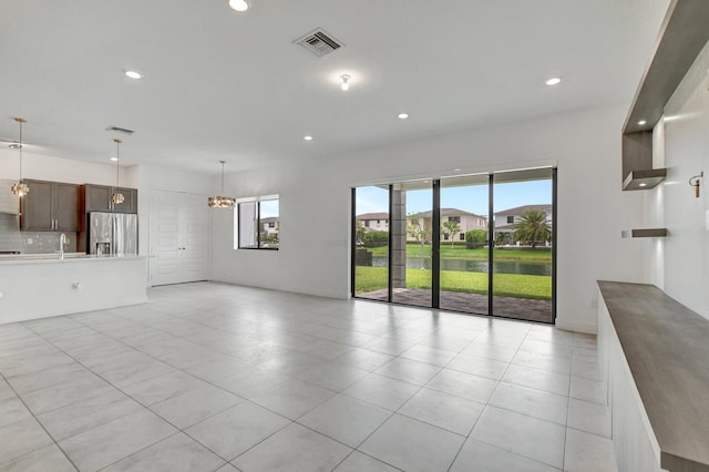 unfurnished living room with a notable chandelier, sink, and light tile patterned flooring