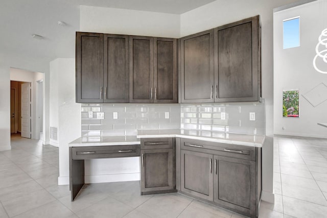 kitchen featuring dark brown cabinetry, backsplash, and light tile patterned floors