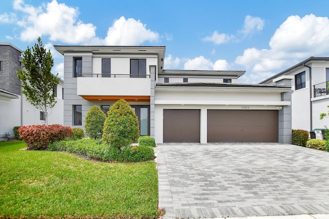 contemporary home featuring a balcony, a garage, and a front yard