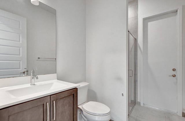 bathroom with a shower with shower door, vanity, tile patterned flooring, and toilet