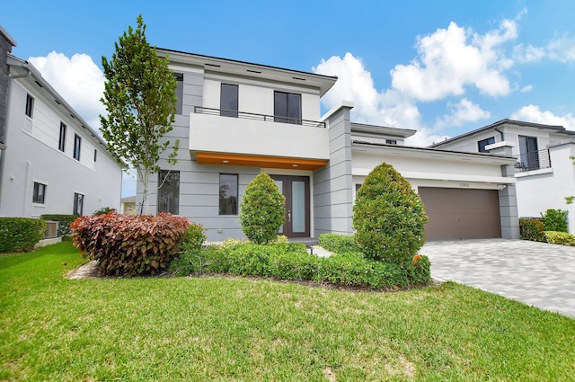 view of front of home with a garage, a balcony, and a front yard