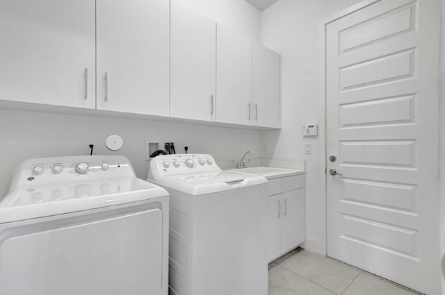 clothes washing area featuring sink, cabinets, washer and dryer, and light tile patterned floors