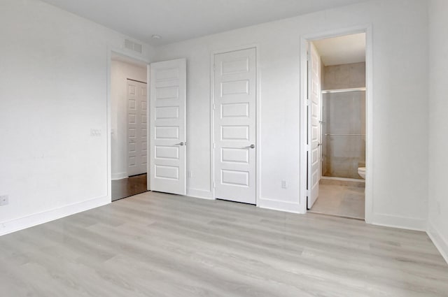 unfurnished bedroom featuring ensuite bath and light wood-type flooring