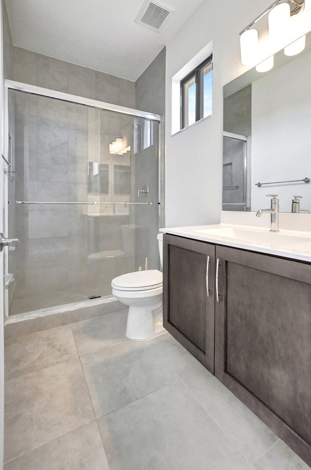 bathroom featuring vanity, toilet, tile patterned floors, and an enclosed shower