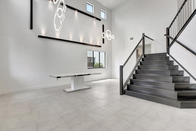 staircase featuring light tile patterned floors, a towering ceiling, and a wealth of natural light